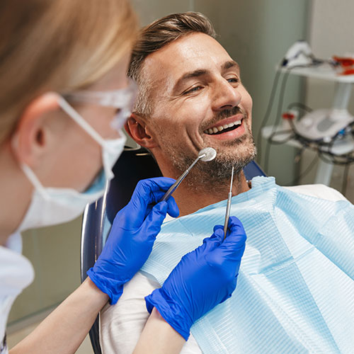middle-aged-man-in-dentists-chair young woman holding aligners