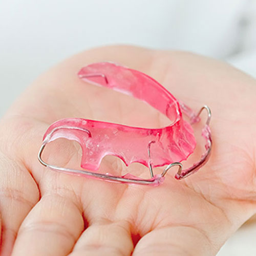 orthodontist-holding-retainer retainers