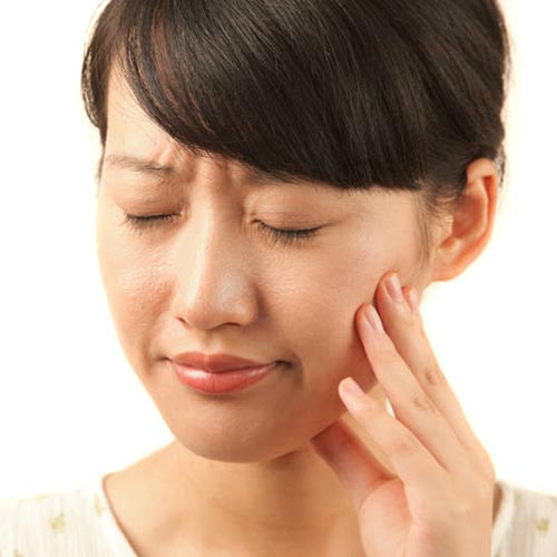 woman-tooth-pain-hold-mouth-cheek young woman holding aligners